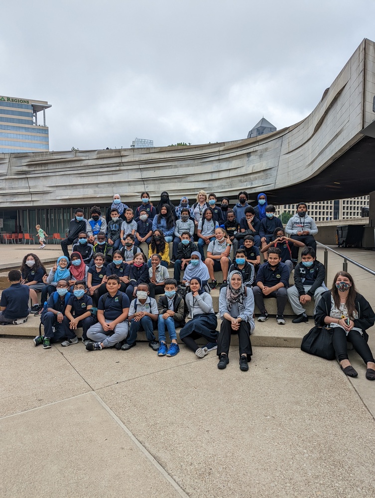 A large group of students and teachers pose for a photo outside the Perot museum in Dallas, TX.