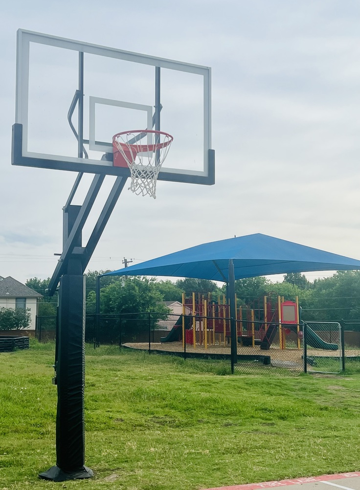 Basketball hoop and blue playground awning covering playground equipment